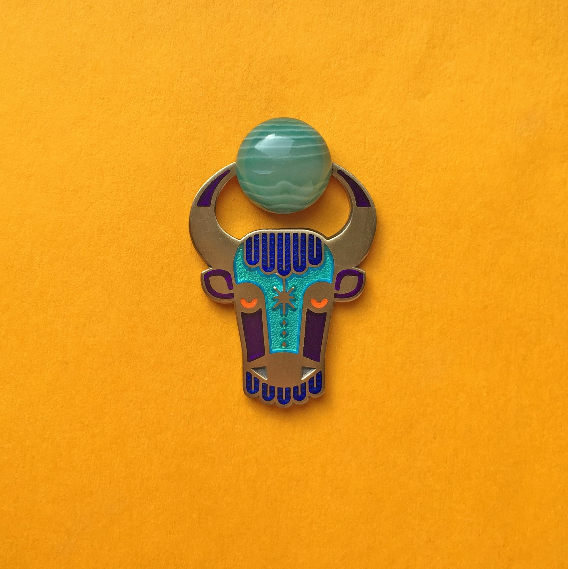 Enzu enamel bull or taurus pin in antique gold, with green agate cabochon between its horns.