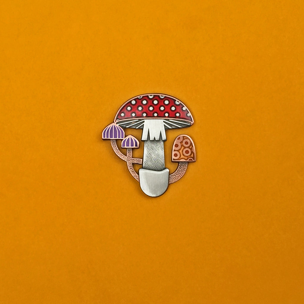Mycelia mushroom enamel pin in antique copper and silver. With translucent red, purple and orange enamel.