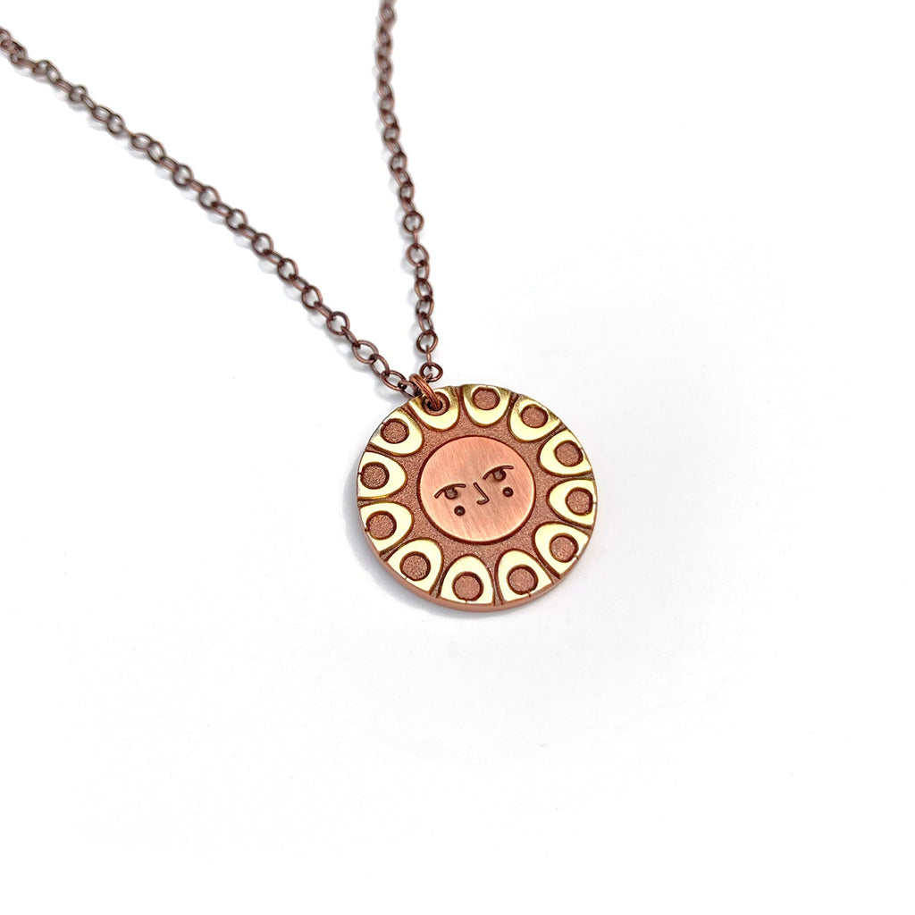 Helios solar necklace finished in 24k gold and antique copper. Has a classic sun face.