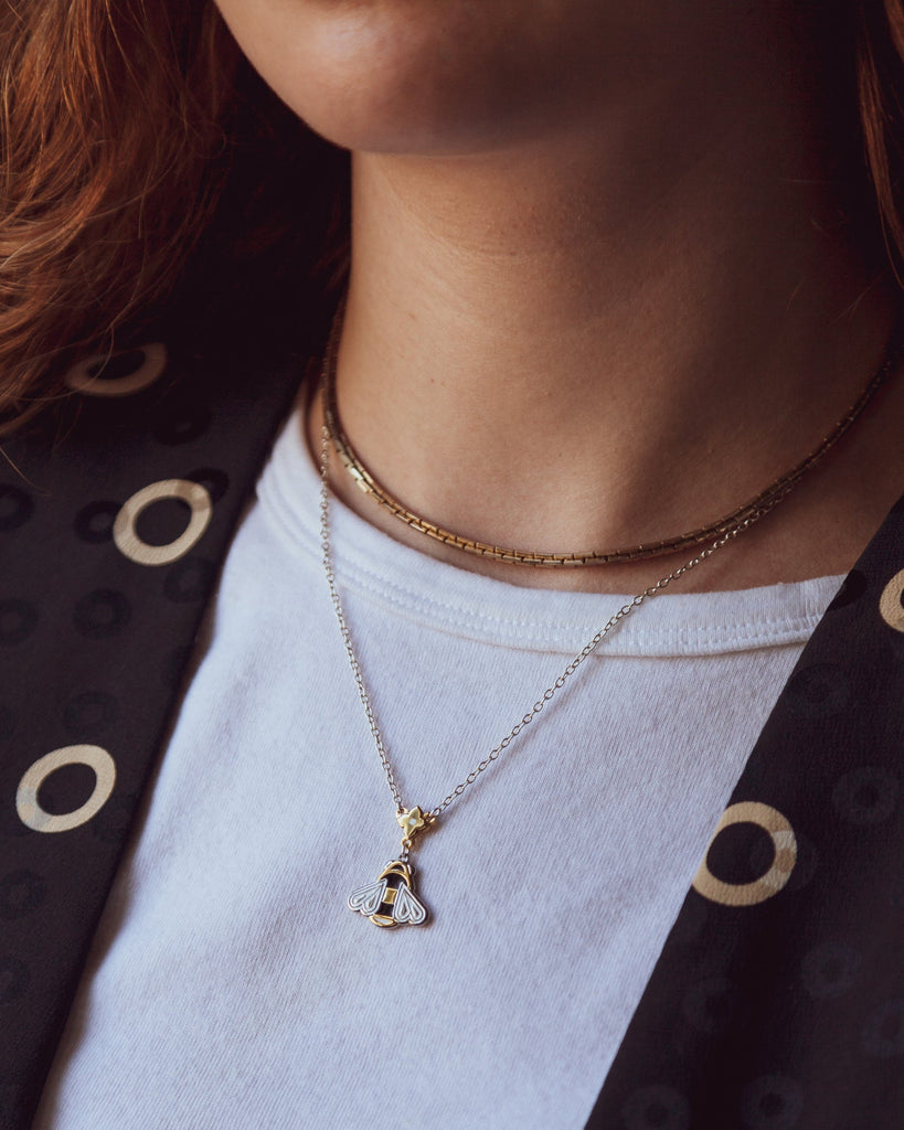 A person wearing a Mellona honeybee necklace showing how it sits near the collarbone.