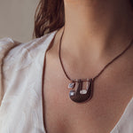 A person wearing Slothlorien sloth and cub necklace, showing how it sits near the collar bone.