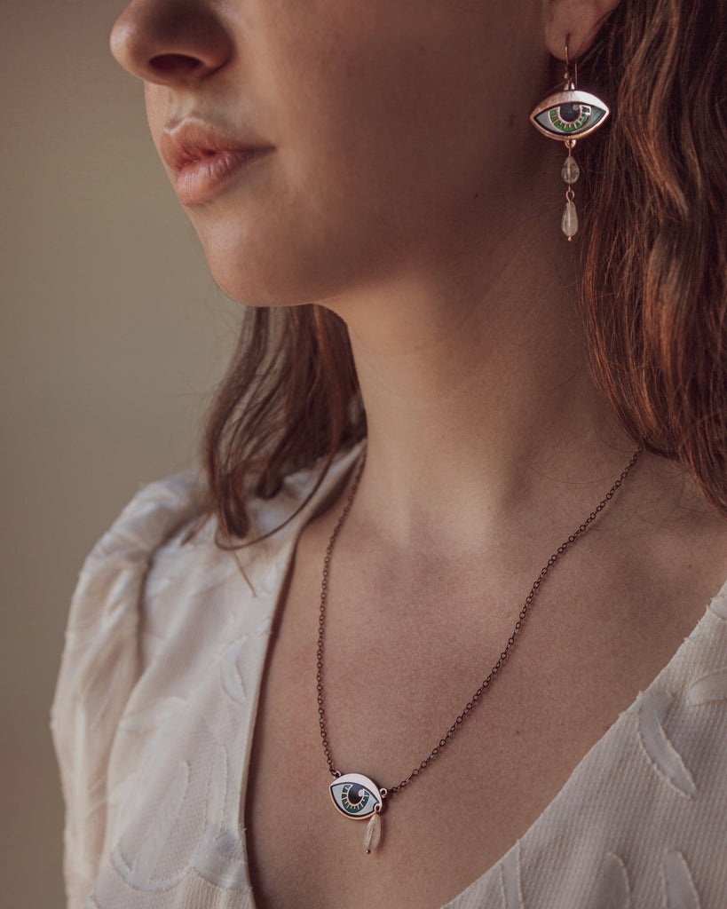 A person wearing a jade blue Ersa eye necklace and earring as a suite.