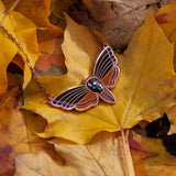 Atropos enamel death's-head moth necklace in copper seconds with black mirrored siofourite crystal skull among autumn leaves.