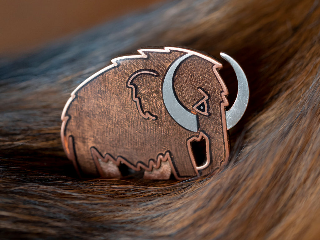 Woolly Mammoth enamel pin in silver with translucent brown enamel.