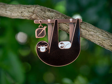 Slothlorien sloth and sleeping cub enamel pin seconds in antique copper. Black enamel, with white cub and leaf dangle.