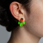 A person wearing Coccinella enamel ladybug or ladybird stud and leaf jacket earrings.