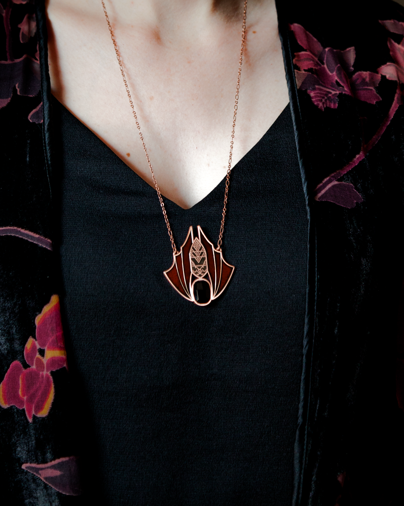 A person wearing a Minyades bat necklace showing how it sits just below the collarbone.
