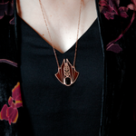 A person wearing a Minyades bat necklace showing how it sits just below the collarbone.