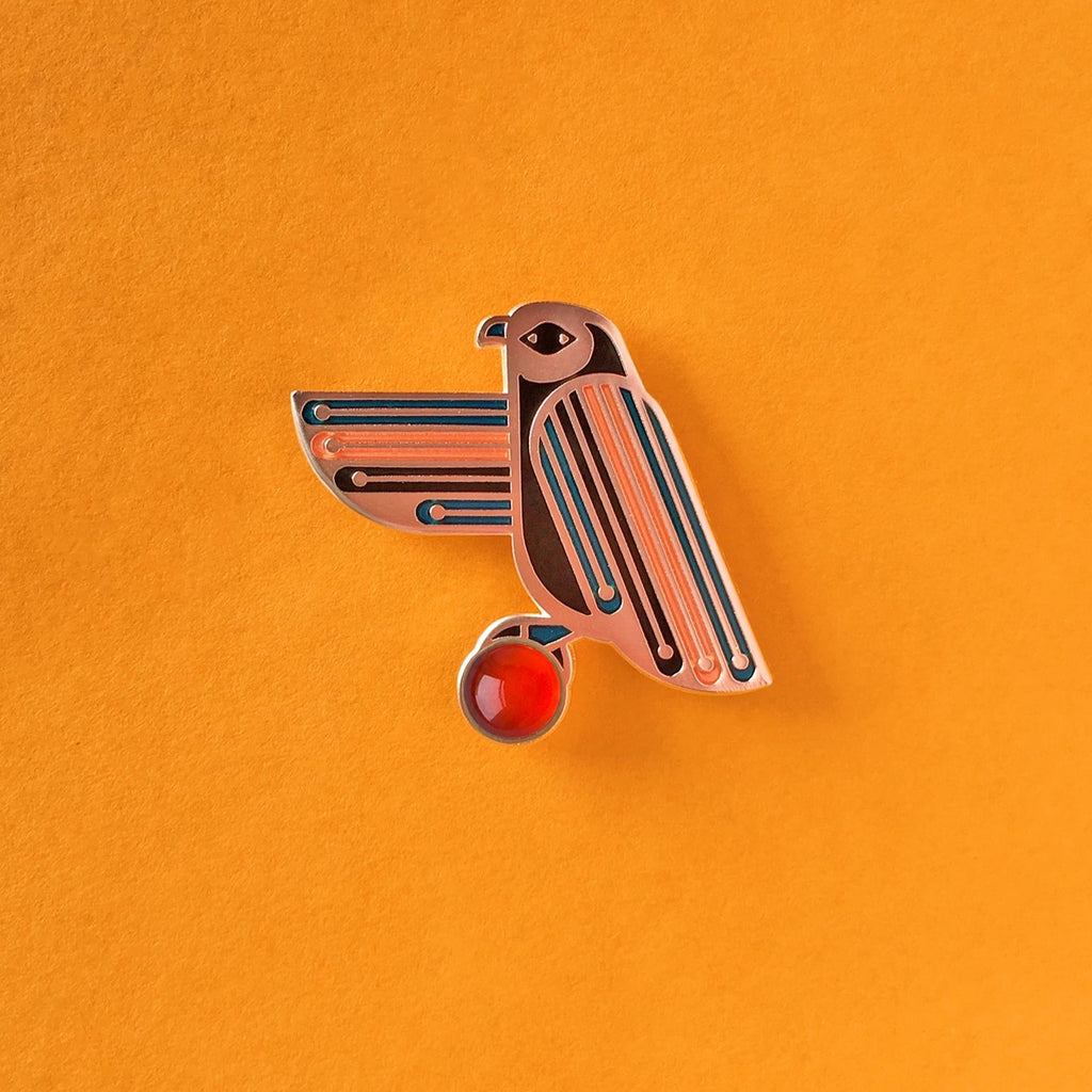 Apollos enamel hawk pin with carnelian cabochon and blue, black and orange stripes.
