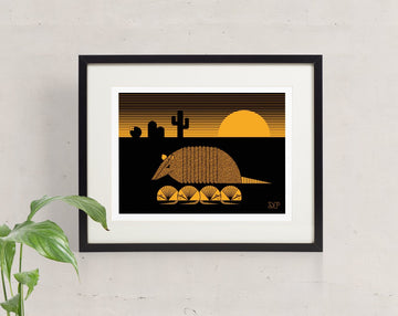 Karmadillo screen print in orange and black of a nine banded armadillo with pups and saguaro cactus during a desert sunset.