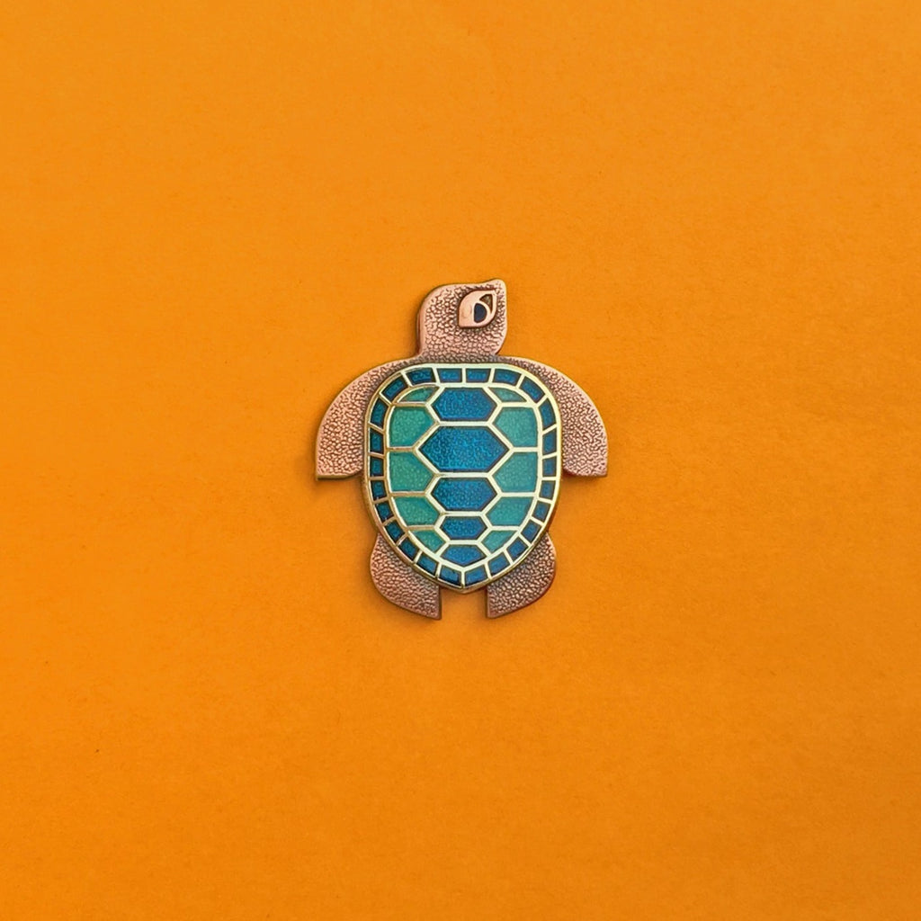 Caretta sea turtle pin set in copper and gold with blue and green enamel.