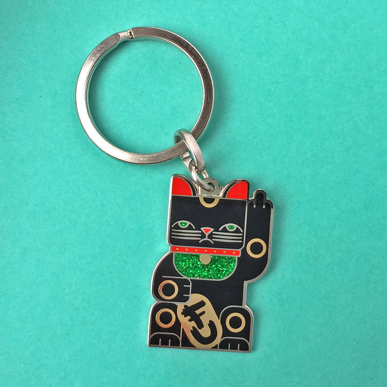 Goodbye Kitty black enamel maneki neko split-ring keychain finished in gold and black with green glitter bib.