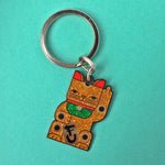 Goodbye Kitty gold glitter enamel maneki neko split-ring keychain finished in gold and black with green glitter bib.