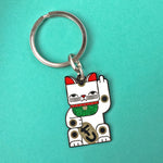 Goodbye Kitty white enamel maneki neko split-ring keychain finished in gold and black with green glitter bib.