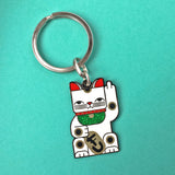Goodbye Kitty white enamel maneki neko split-ring keychain finished in gold and black with green glitter bib.
