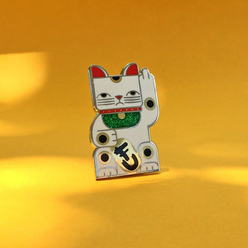 Goodbye Kitty white enamel pin seconds in gold and silver with green glitter bib. Shows a maneki neko rudely gesturing.
