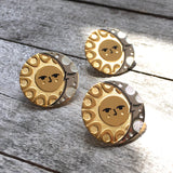 A group of Illumine solar and lunar enamel pins in gold and silver. With a classic sun face and sleeping moon.