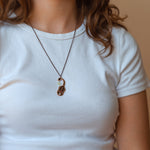 A person wearing an Ishara scorpion black enamel necklace. Shows where it sits just below the collarbone.