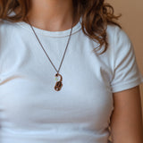 A person wearing an Ishara scorpion black enamel necklace. Shows where it sits just below the collarbone.