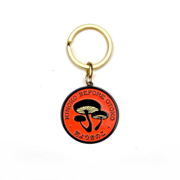 Kinoko Before Otoko, mushrooms before dudes enamel split-ring keychain in orange and black.