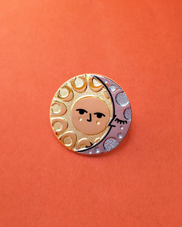 Illumine solar and lunar enamel pin in gold and silver. With a classic sun face and sleeping moon.