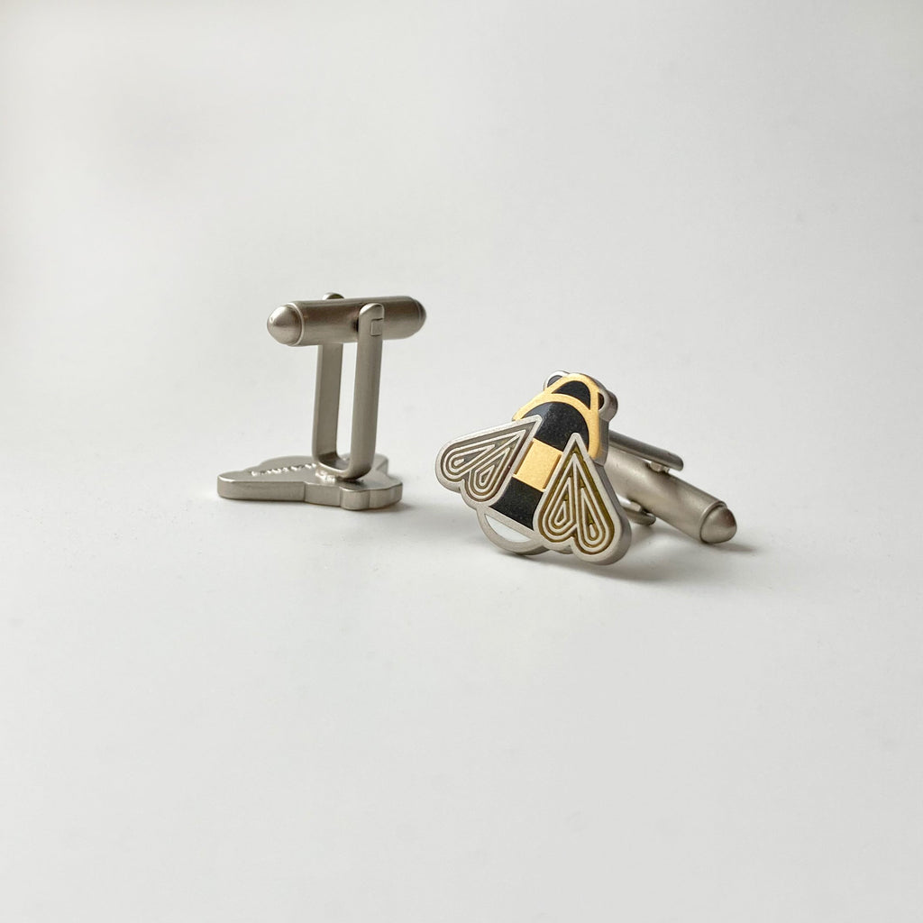 Mellona black and white enamel honeybee cufflinks finished in 24k gold and satin sterling silver showing bullet toggle backs.