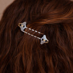 A person wearing a pair of Mellona black and white enamel honeybee hairpins in gold and silver.