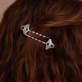 A person wearing a pair of Mellona black and white enamel honeybee hairpins in gold and silver.