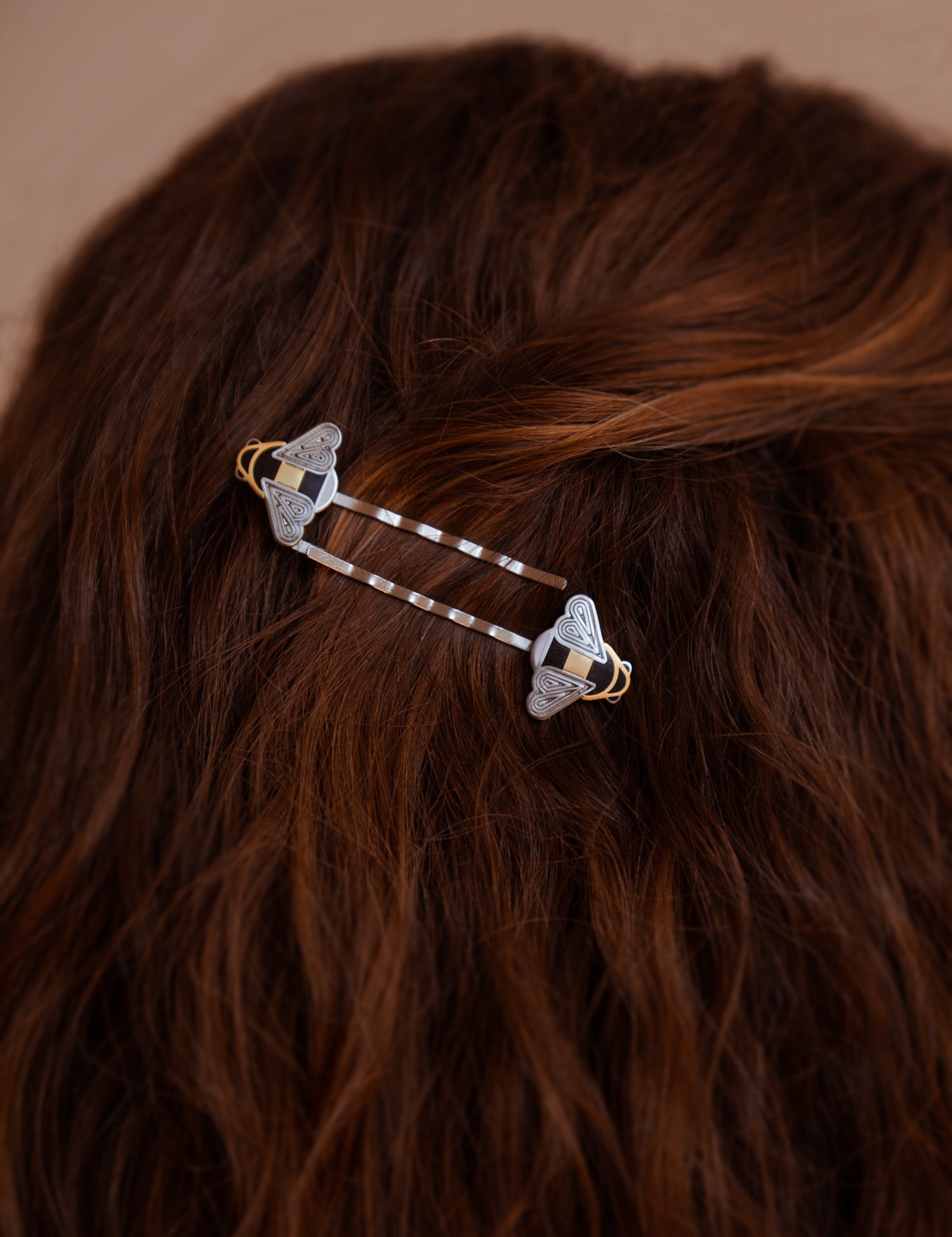 A person wearing a pair of Mellona black and white enamel honeybee hairpins in gold and silver.