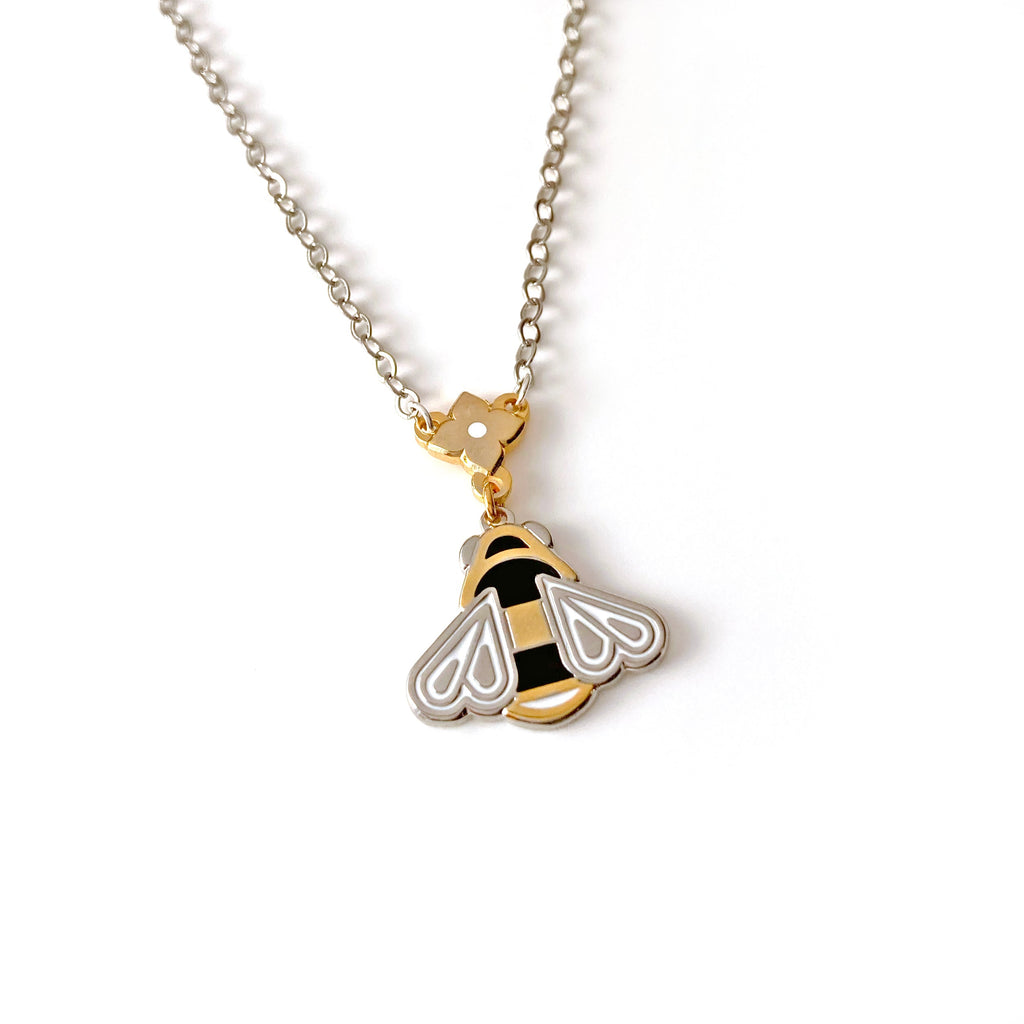 Mellona black and white enamel honeybee necklace with gold flower finding and 24k and satin sterling silver finish.