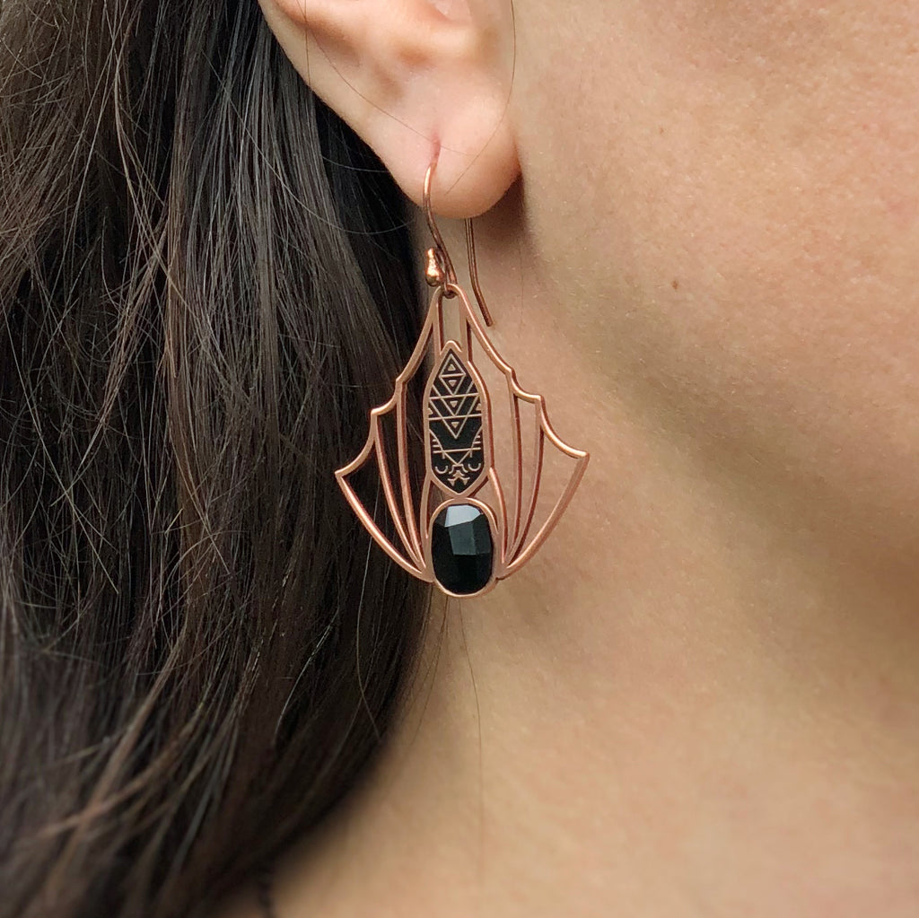 A person wearing a Minyades bat earring showing the copper wire hook.