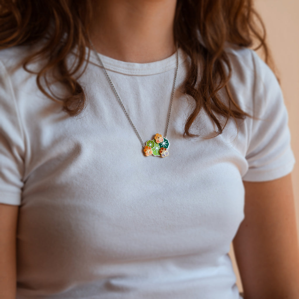 A person wearing a Nasturtium necklace showing it sitting at around the collarbone.