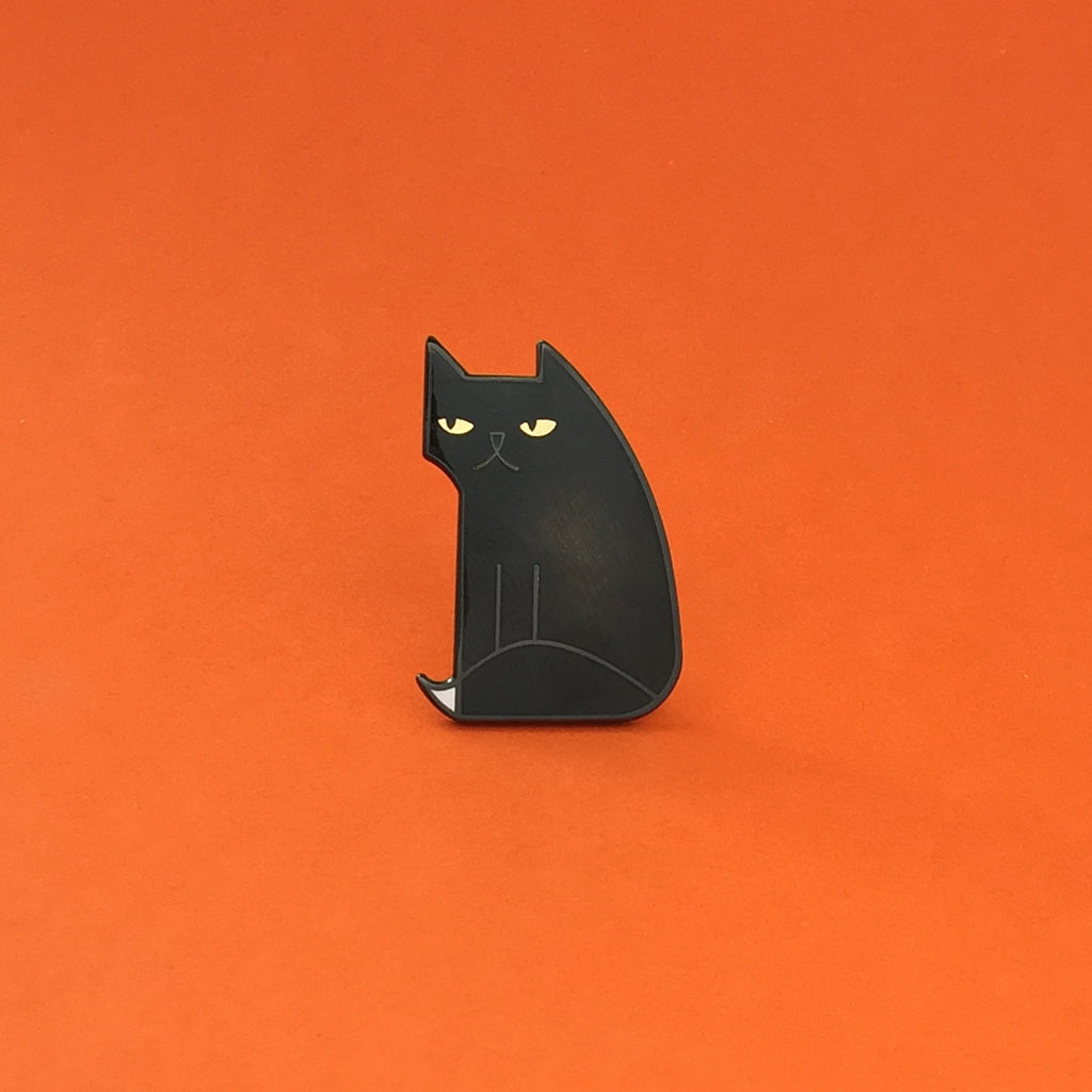 Not Amewsed black enamel cat pin seconds in black finish, with gold eyes and white-tipped tail.