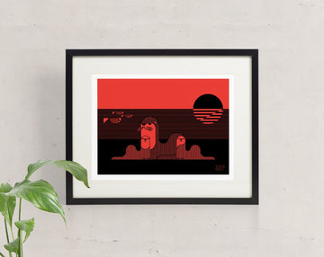 An Otter Day In Paradise screen print framed and hung on the wall, showing three otters relaxing on the beach during sunset.