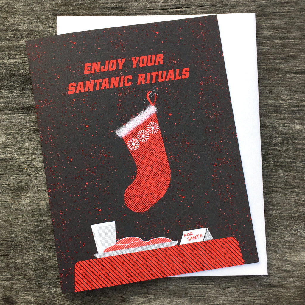 Enjoy Your Santanic Rituals christmas greeting card in black and red. Depicts a stocking, milk and cookies.