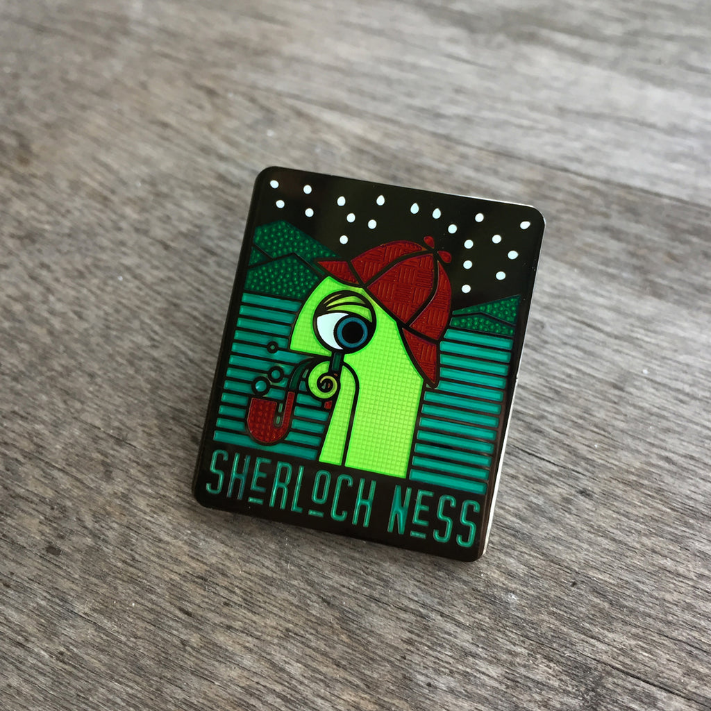 Sherloch Ness enamel pin. Shows a sherloch, loch ness monster with glow in the dark stars.