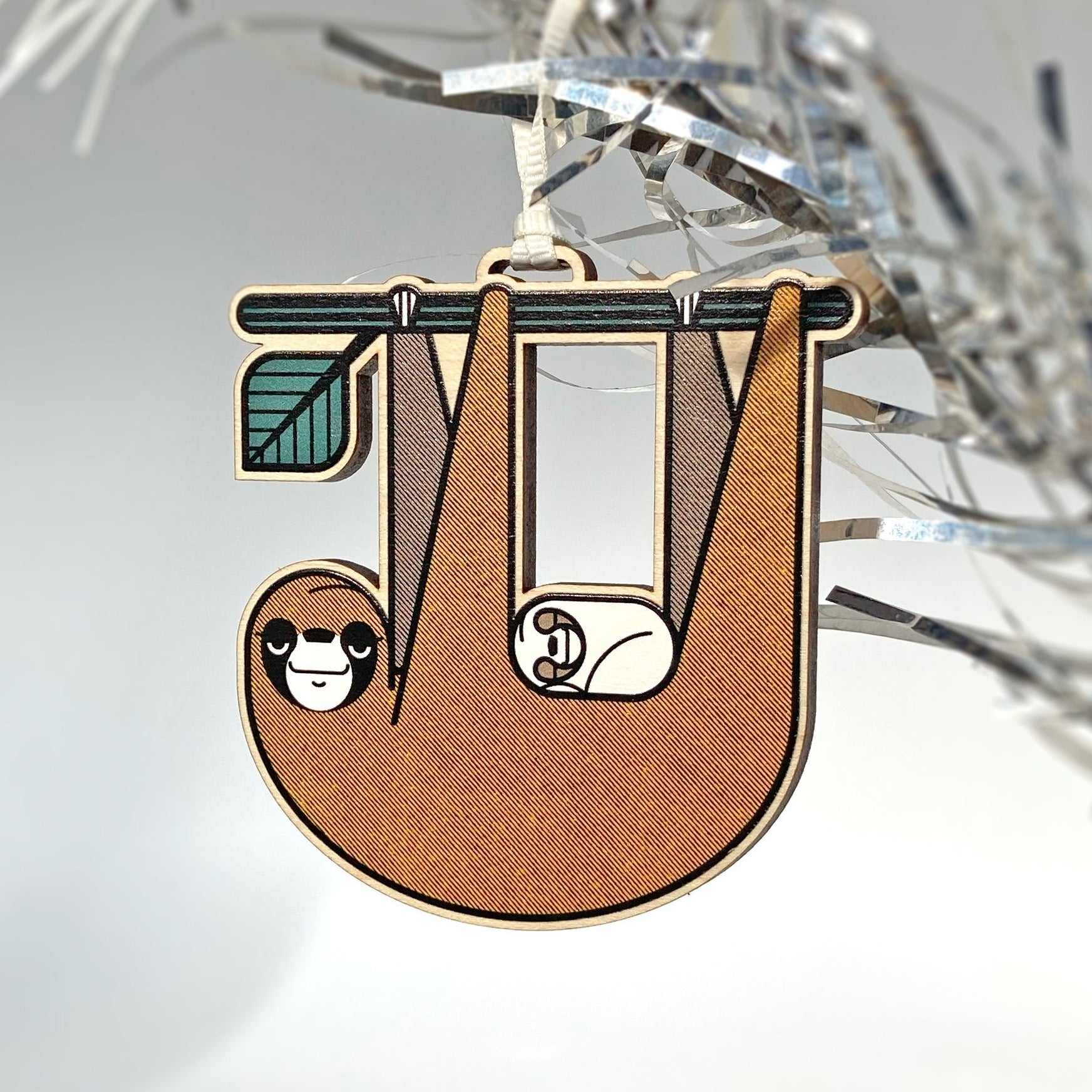 Slothlorien sloth and sleeping cub laser woodcut tree ornament. Printed in brown, black, white and green.