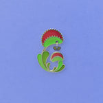 Venus Flytrap enamel pin. Dionaea muscipula in green, red and 24k gold finish. Fly dangle in silver and translucent wings.