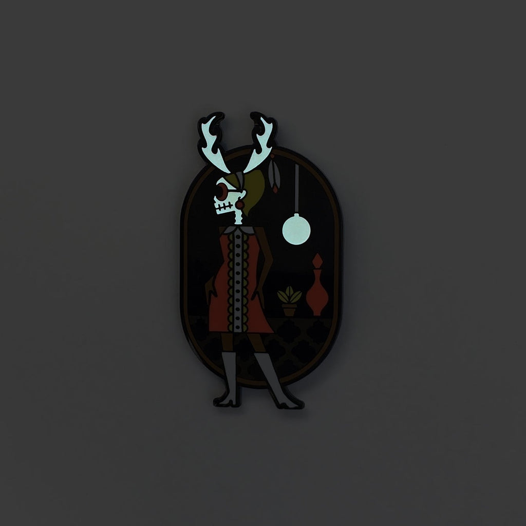 Wendigo-go enamel pin seconds in black metal and fuchsia, black and green enamel. Shows glow in the skull and lamp.