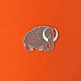 Woolly Mammoth enamel pin in silver with translucent brown enamel.