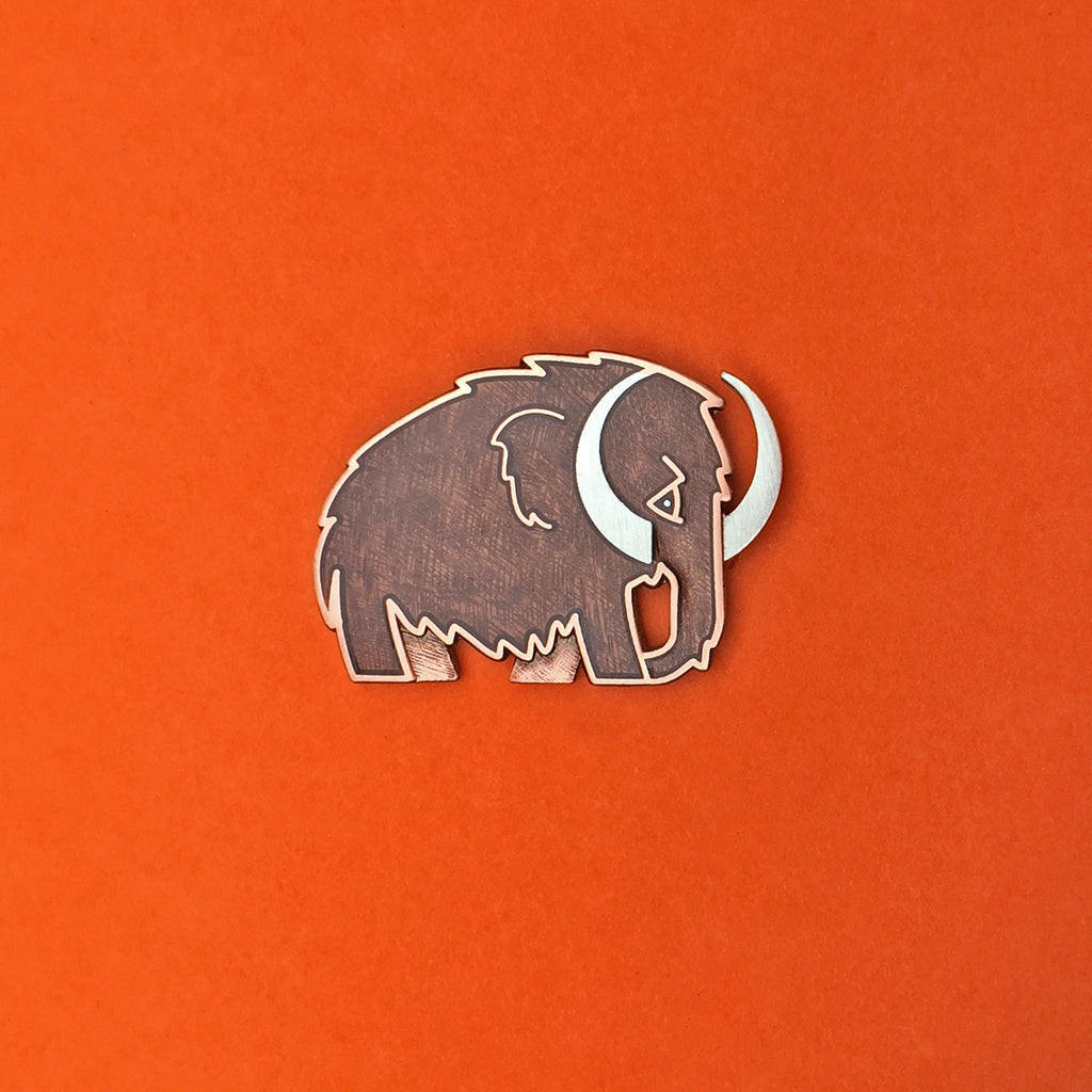 Woolly Mammoth enamel pin in silver with translucent brown enamel.